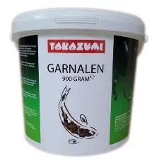 Duże, białe wiadro z zielono-czarną etykietą "TAKZUMI GARNALEN 900 GRAM". Na etykiecie znajduje się grafika ryby koi. Jest to prawdopodobnie opakowanie suszonych krewetek jako przysmak dla ryb.